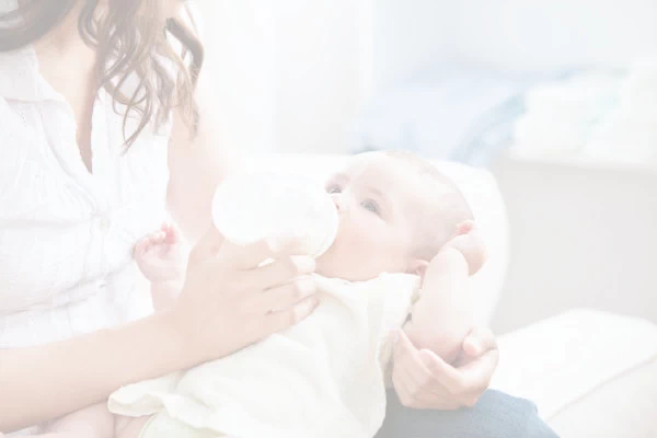 Au pair giving a baby a bottle.